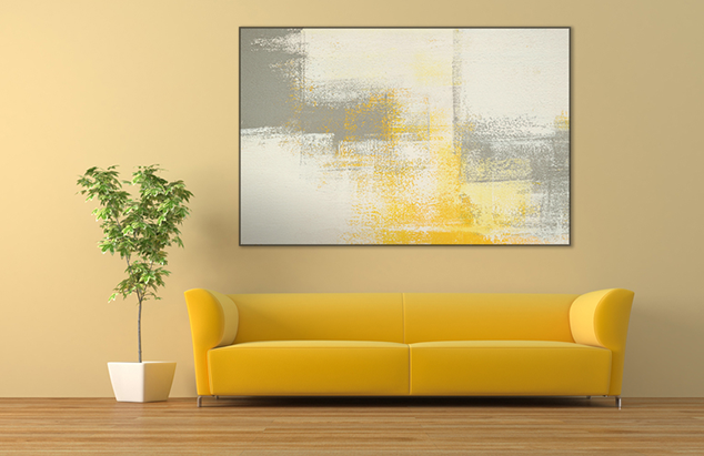 A living room with a yellow couch and a painting on the wall.