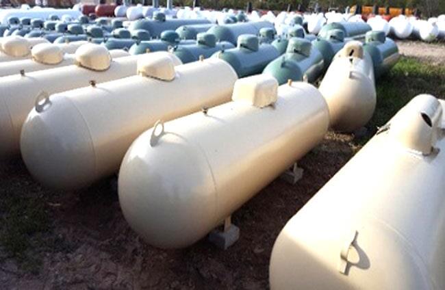 Un montón de tanques de propano están alineados en un campo.