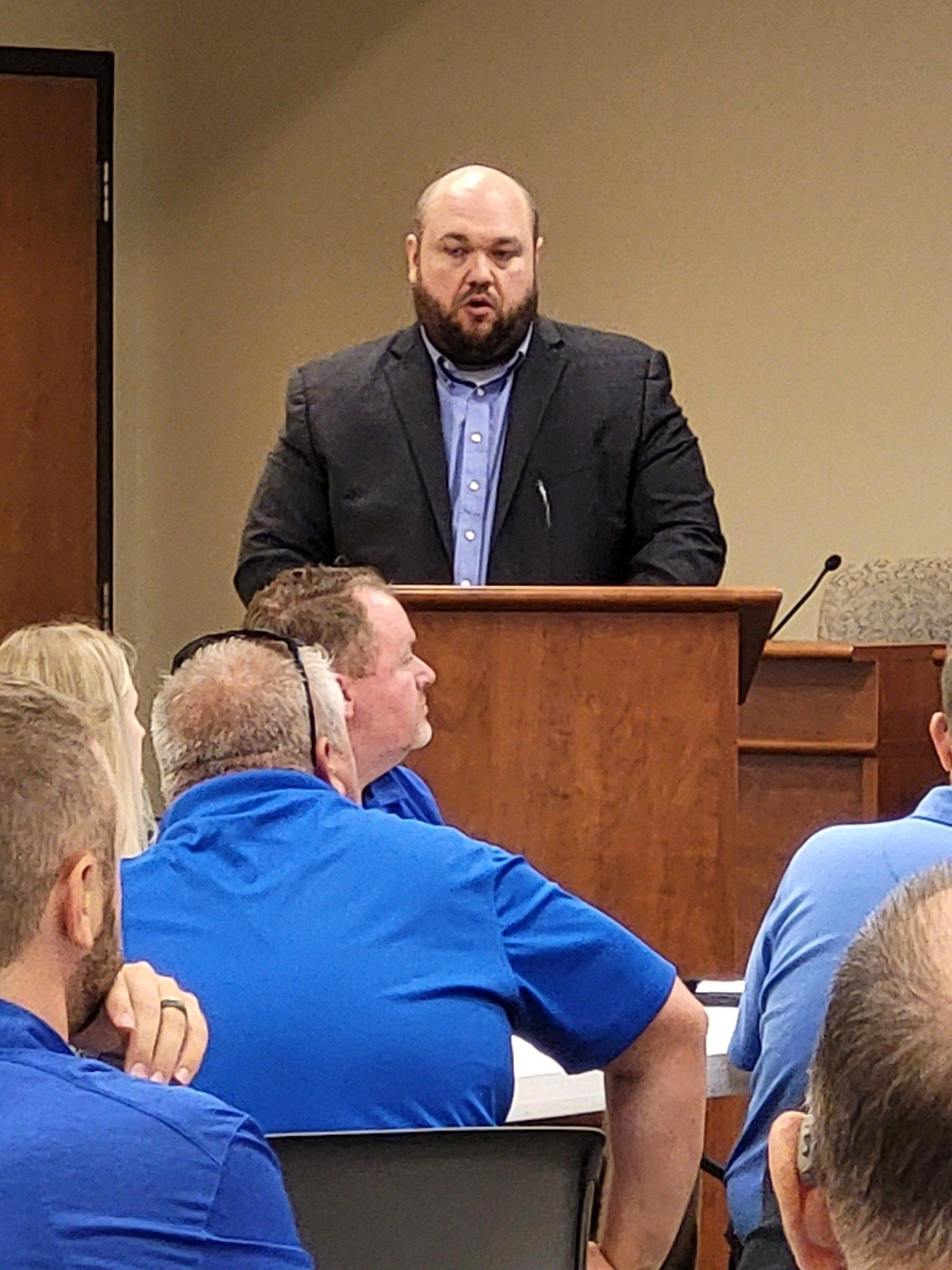 A man is standing at a podium giving a speech to a group of people.