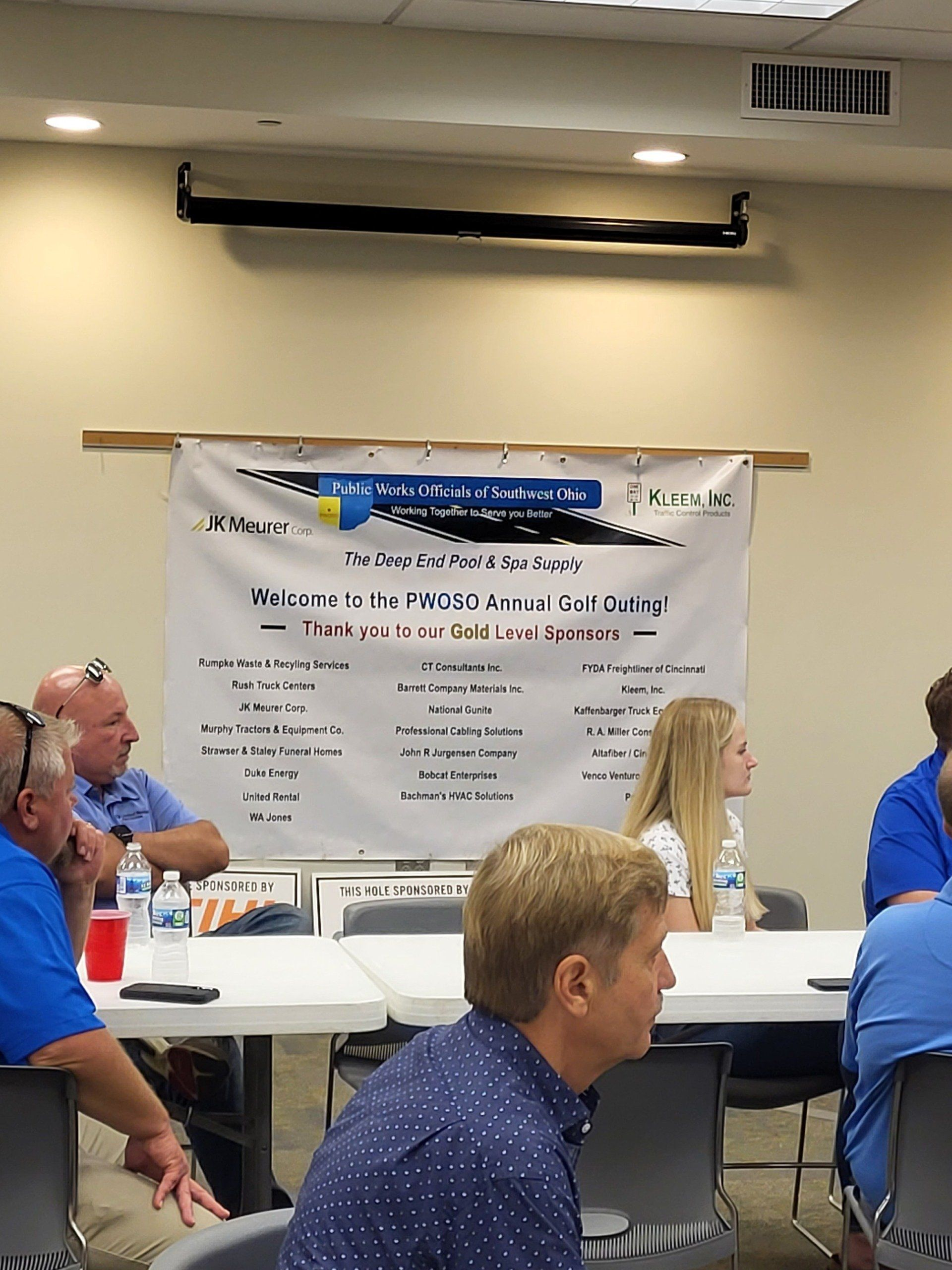 A group of people are sitting at tables in front of a white board.