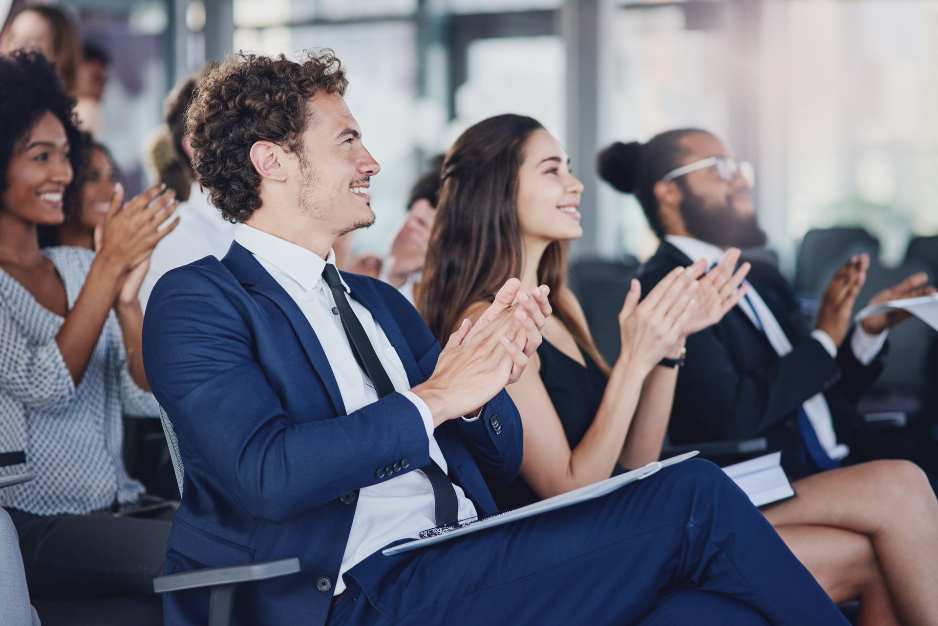 A group of people are sitting in a row clapping their hands.