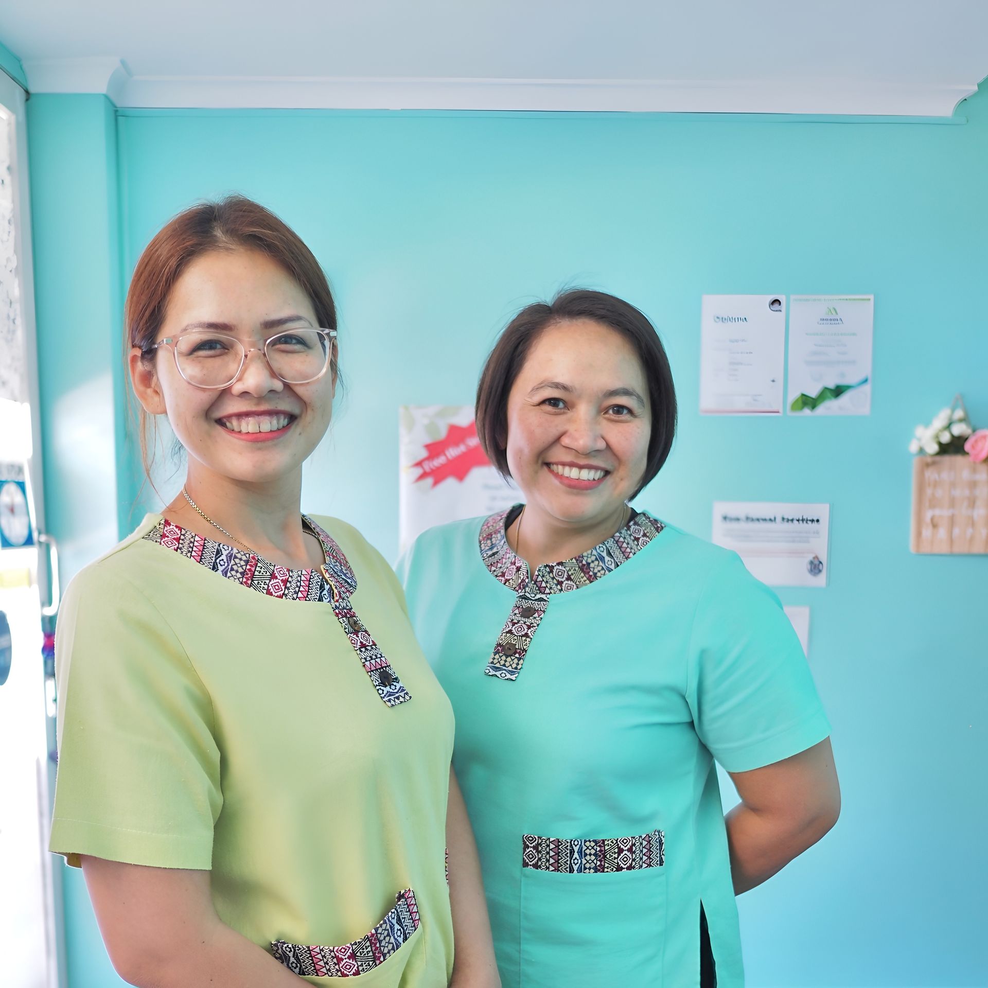 Two Smiling Women in Light Green and Blue Scrubs — First Avenue Remedial Massage in Maroochydore, QLD
