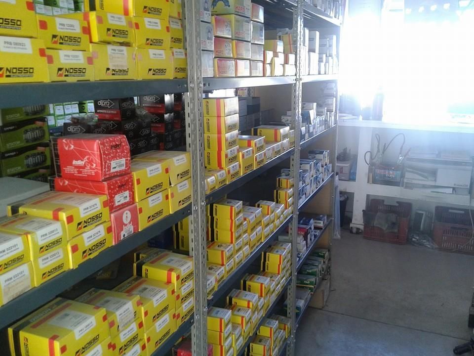 Piezas metálicas de motor y filtros dispuestos en un estante gris en un taller o área de almacenamiento.