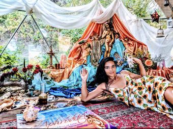 A woman in a sunflower dress is laying on the floor in a tent.