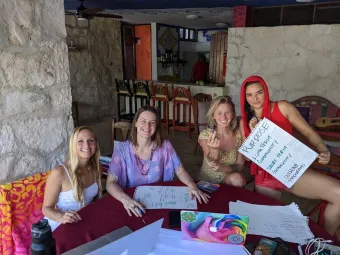A group of women are sitting around a table holding signs.