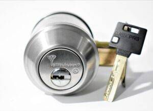 Una cerradura de puerta de acero inoxidable con una llave al lado.