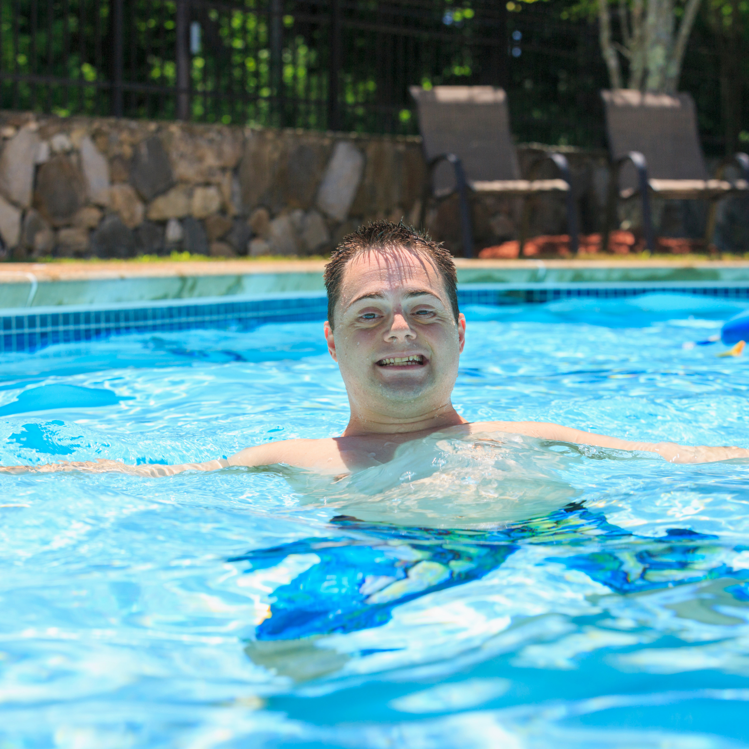 a man is swimming in a swimming pool and smiling at the camera .