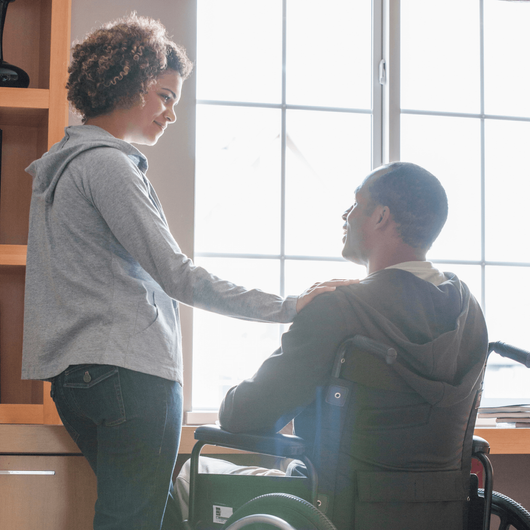 a woman is standing next to a man in a wheelchair .
