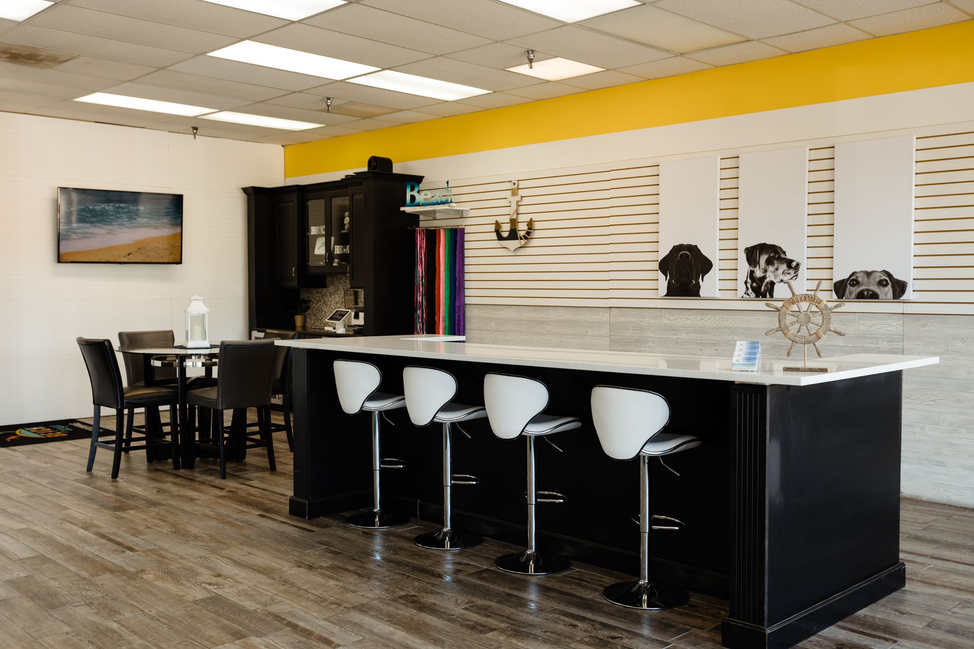 A kitchen with a long black counter and white stools.