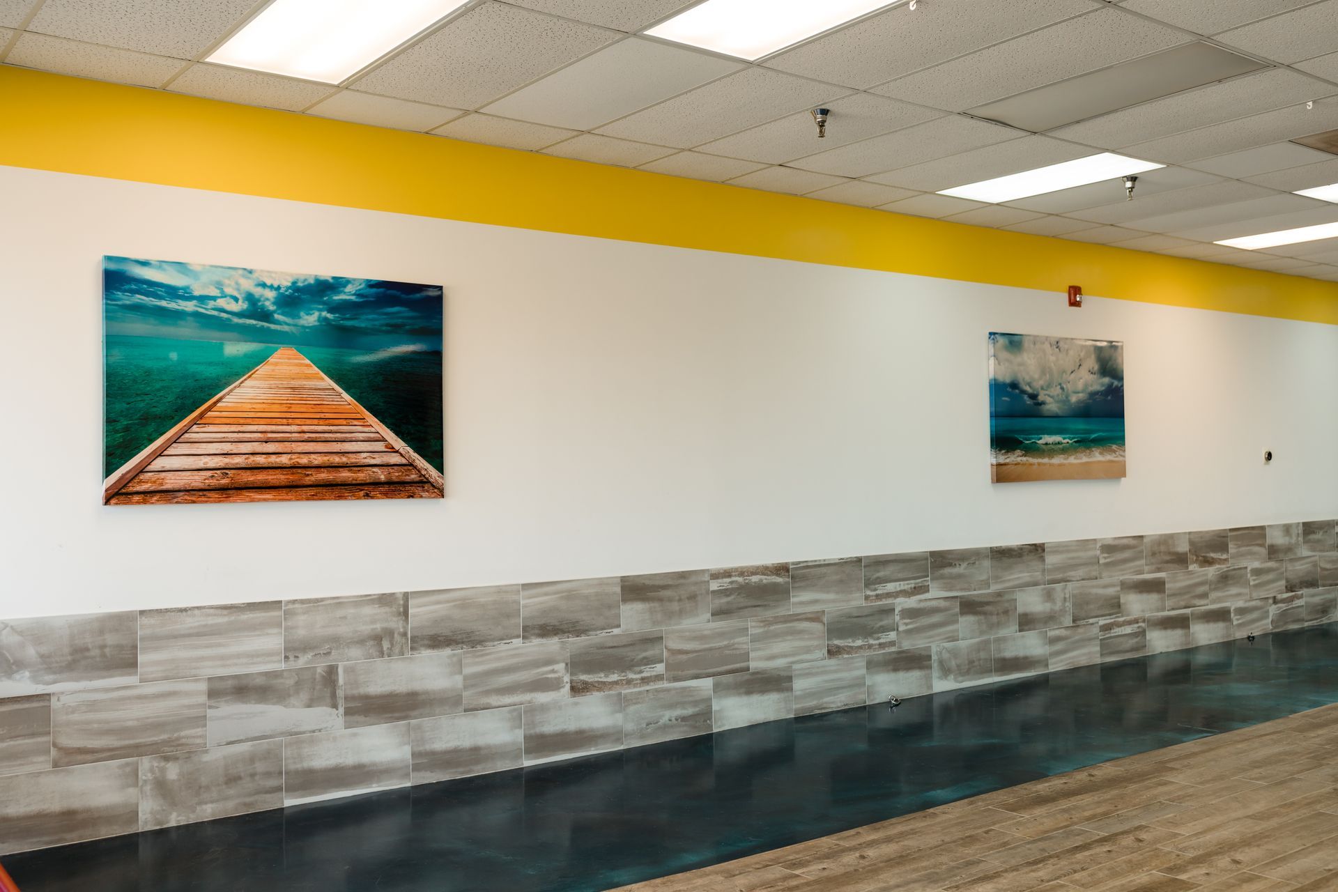 A hallway with paintings on the wall and a wooden dock