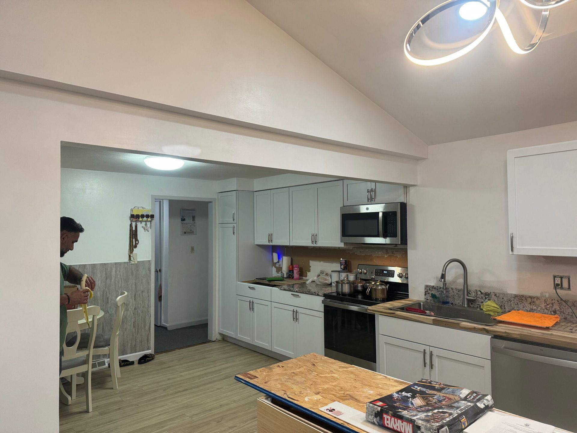 Kitchen interior with white cabinets, stainless steel appliances, and a person in the doorway.