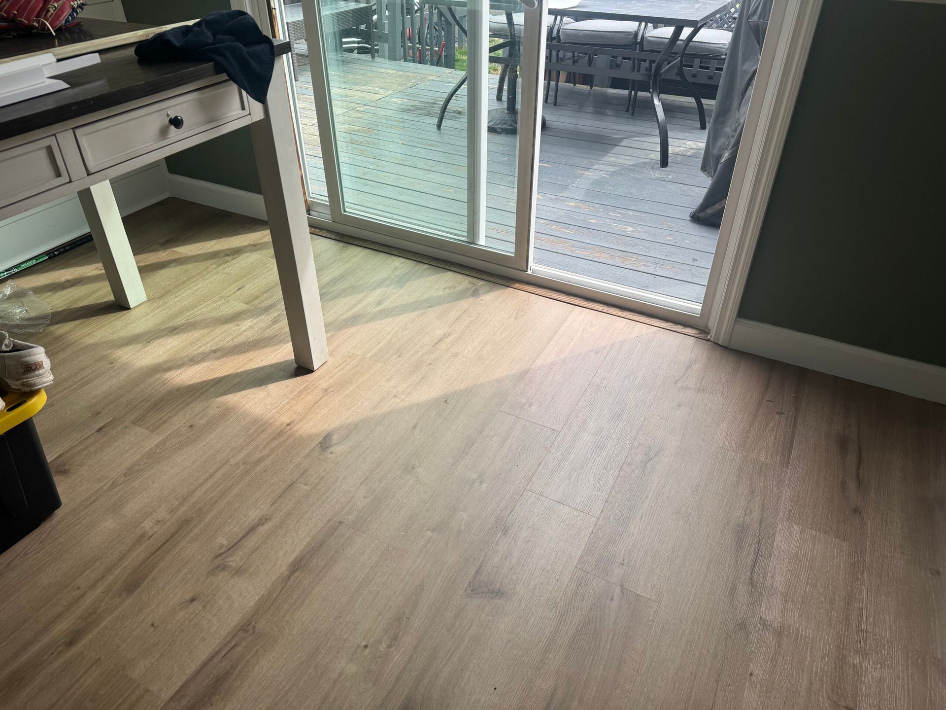 Wooden floor leads to sliding glass door and outdoor patio. A white desk is in the corner.