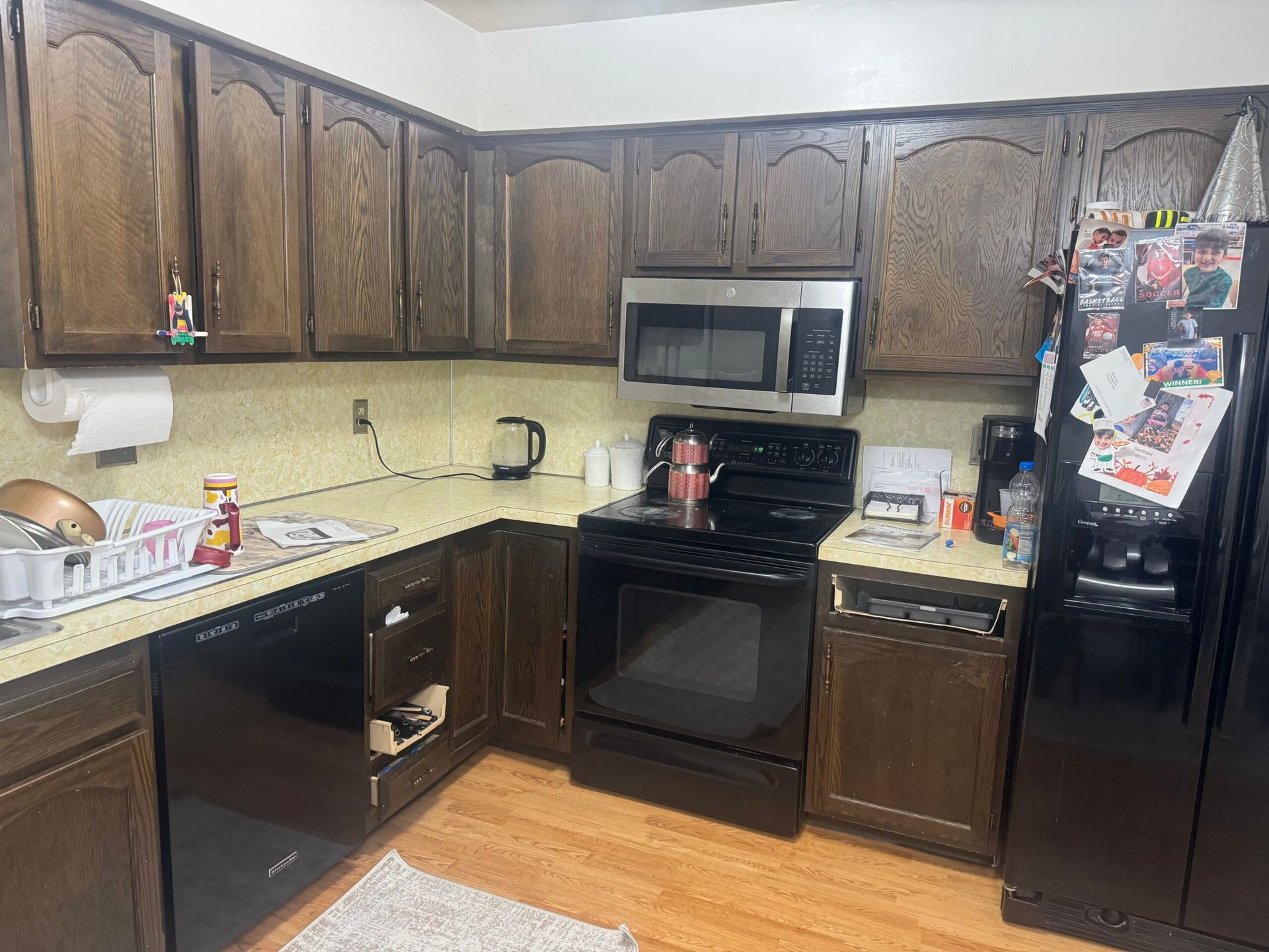 Kitchen with dark brown cabinets, black appliances, and light wood floors.