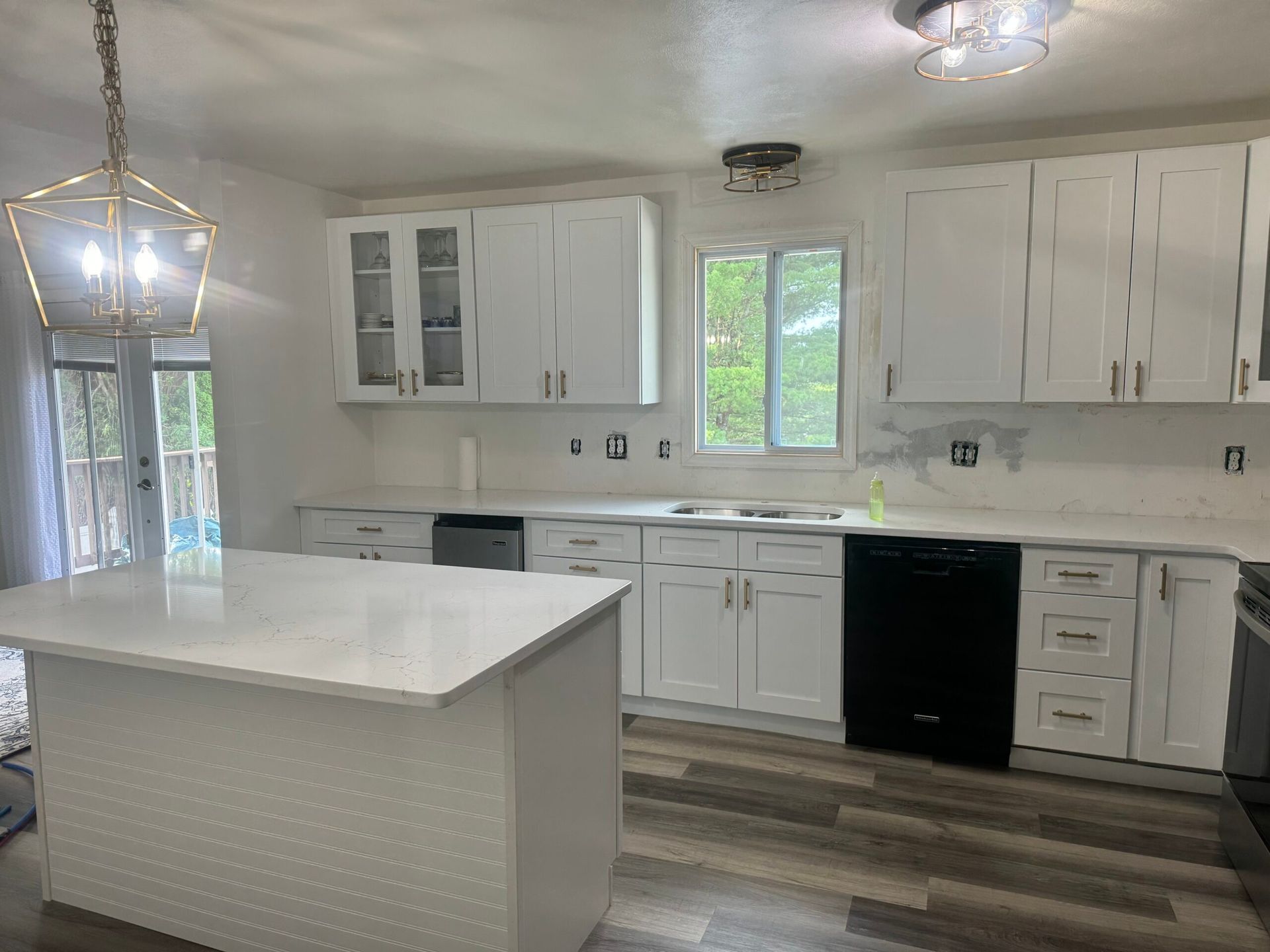White kitchen with island, cabinets, and appliances; light gray flooring.