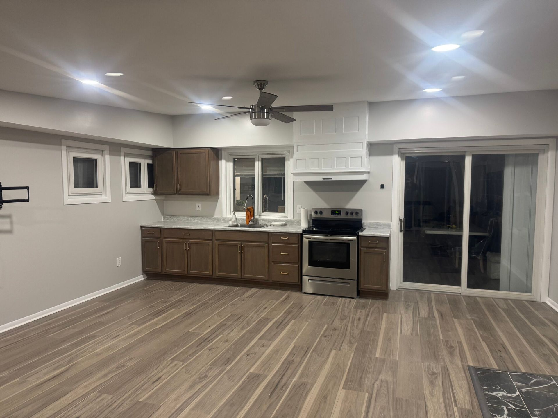 Modern kitchen with brown cabinets, stainless steel appliances, and sliding glass door.