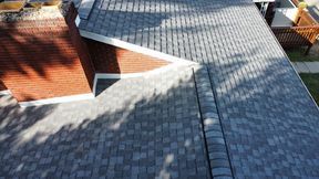 Aerial view of a gray asphalt shingle roof, with brick exterior, and a white trim.