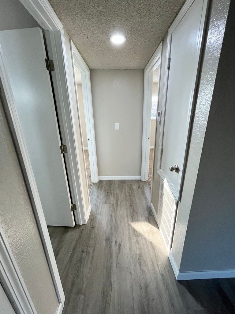 Narrow hallway with gray flooring, white doors, and a ceiling light.