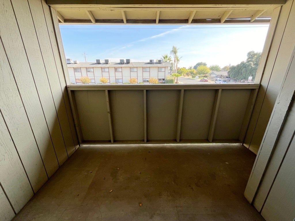 View from an outdoor balcony overlooking buildings and a blue sky on a sunny day.