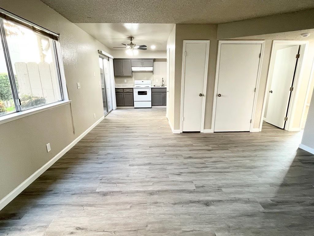 Interior apartment view with gray flooring, kitchen, and closed white doors.