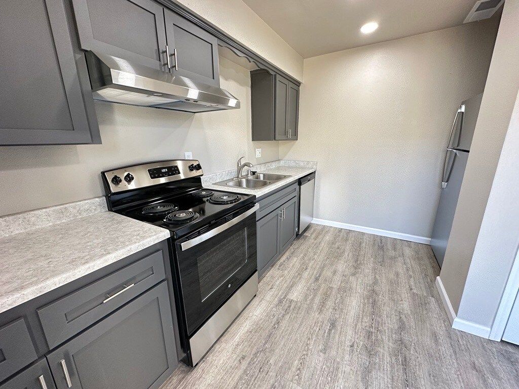 Gray kitchen with stainless steel appliances, cabinets, and light wood flooring.