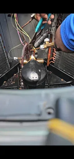 Person uses pliers on air conditioner components.