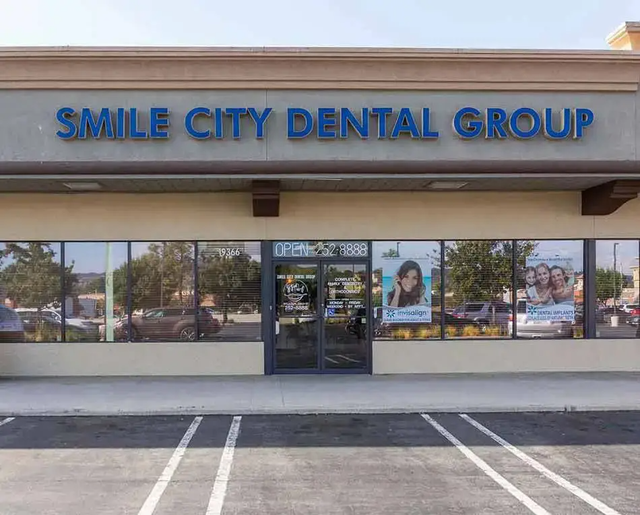 The front of a smile city dental group with a parking lot in front of it.