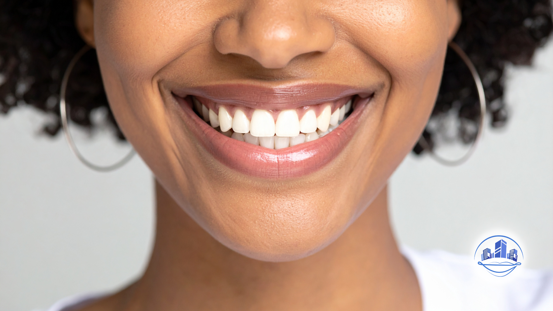 Close-up of a person's mouth, showing slightly discolored teeth and a mole on the chin.