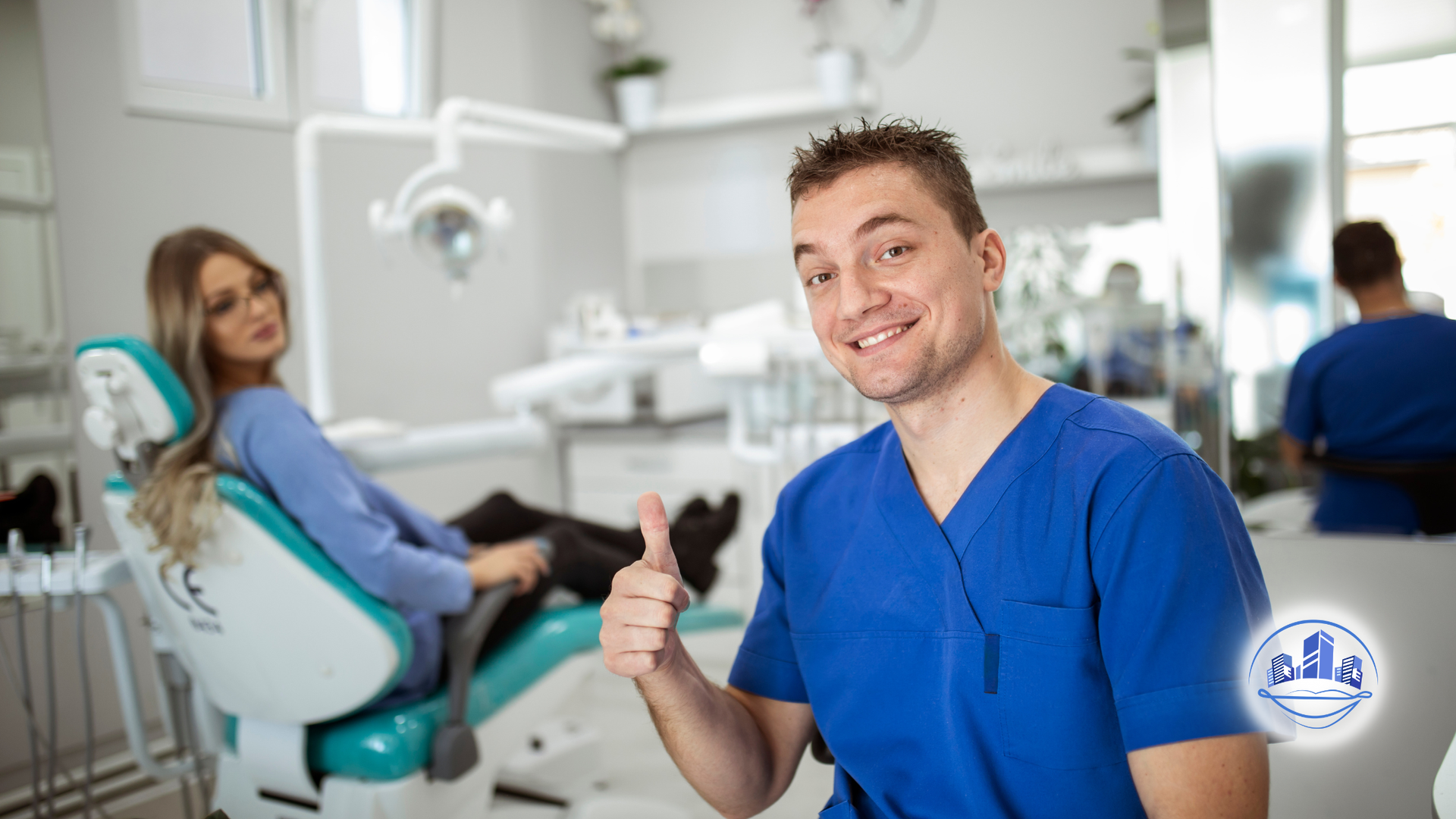 Dentist in blue scrubs giving a thumbs up in a dental office; patient in chair.