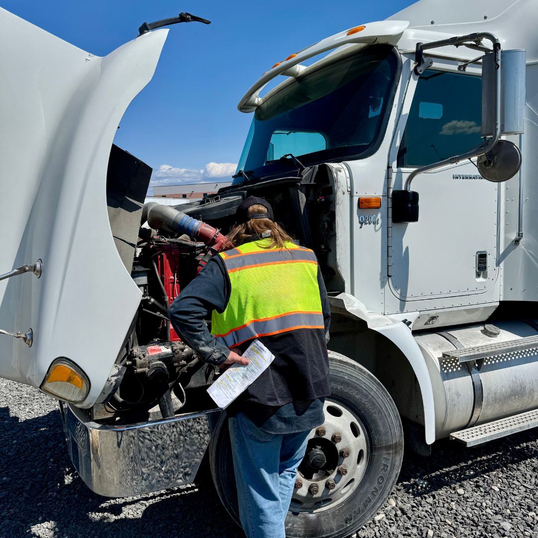 CDL student looking into the semi truck engine bay, learning the ELDT curriculum.