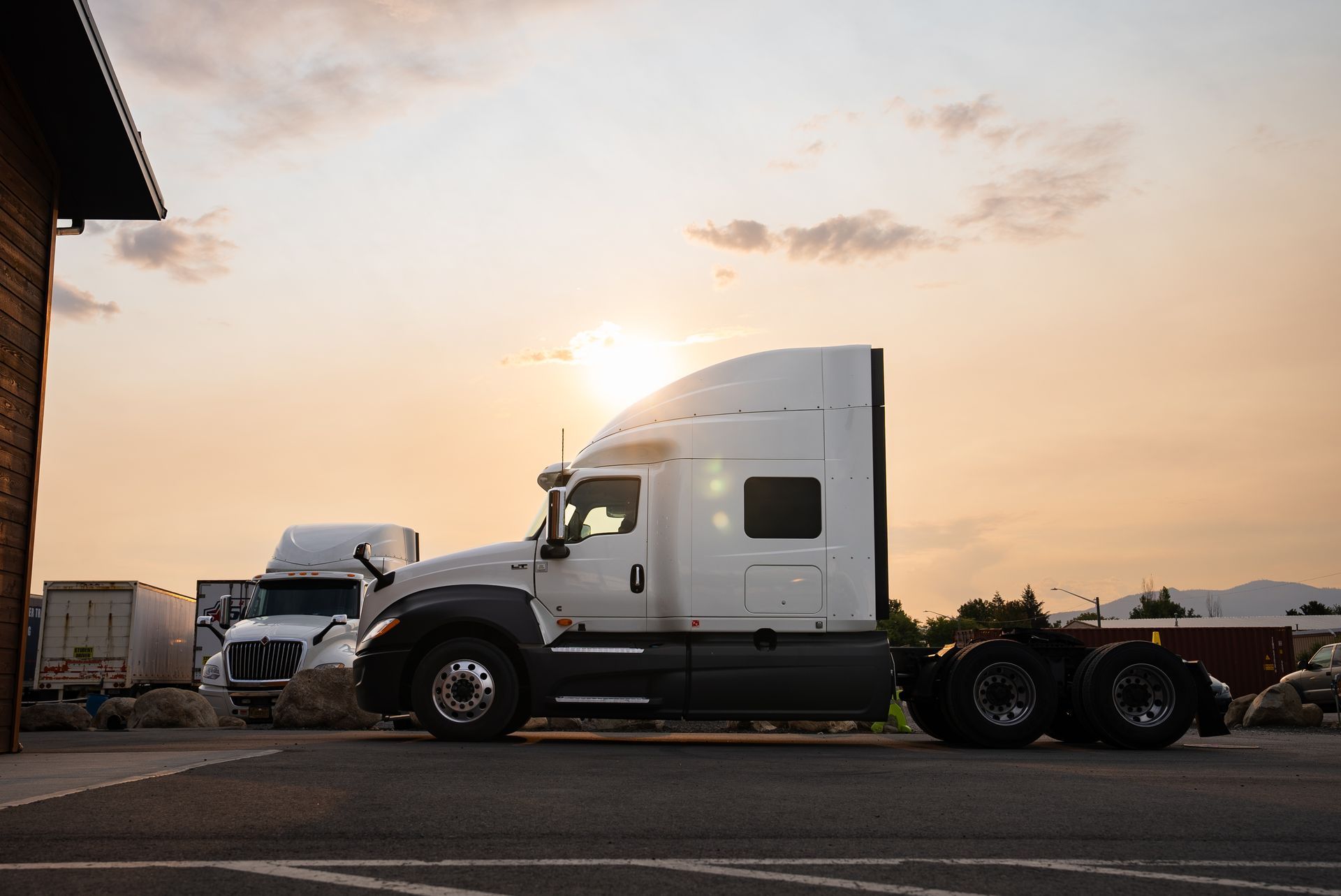 A semi truck is parked in a parking lot at a CDL school at sunset.