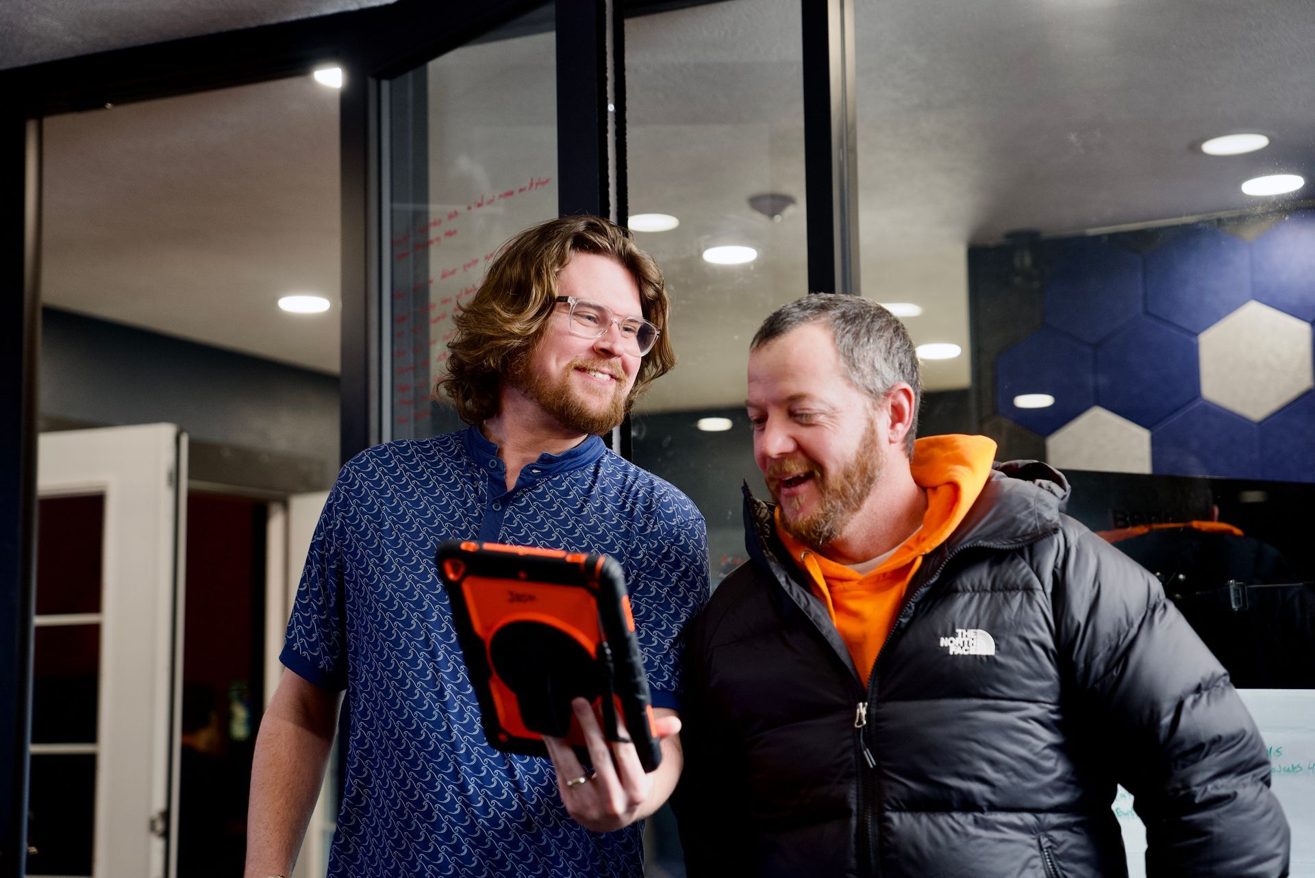Two men are standing next to each other, looking at a tablet, discovering they can do CDL training Online with ELDT theory
