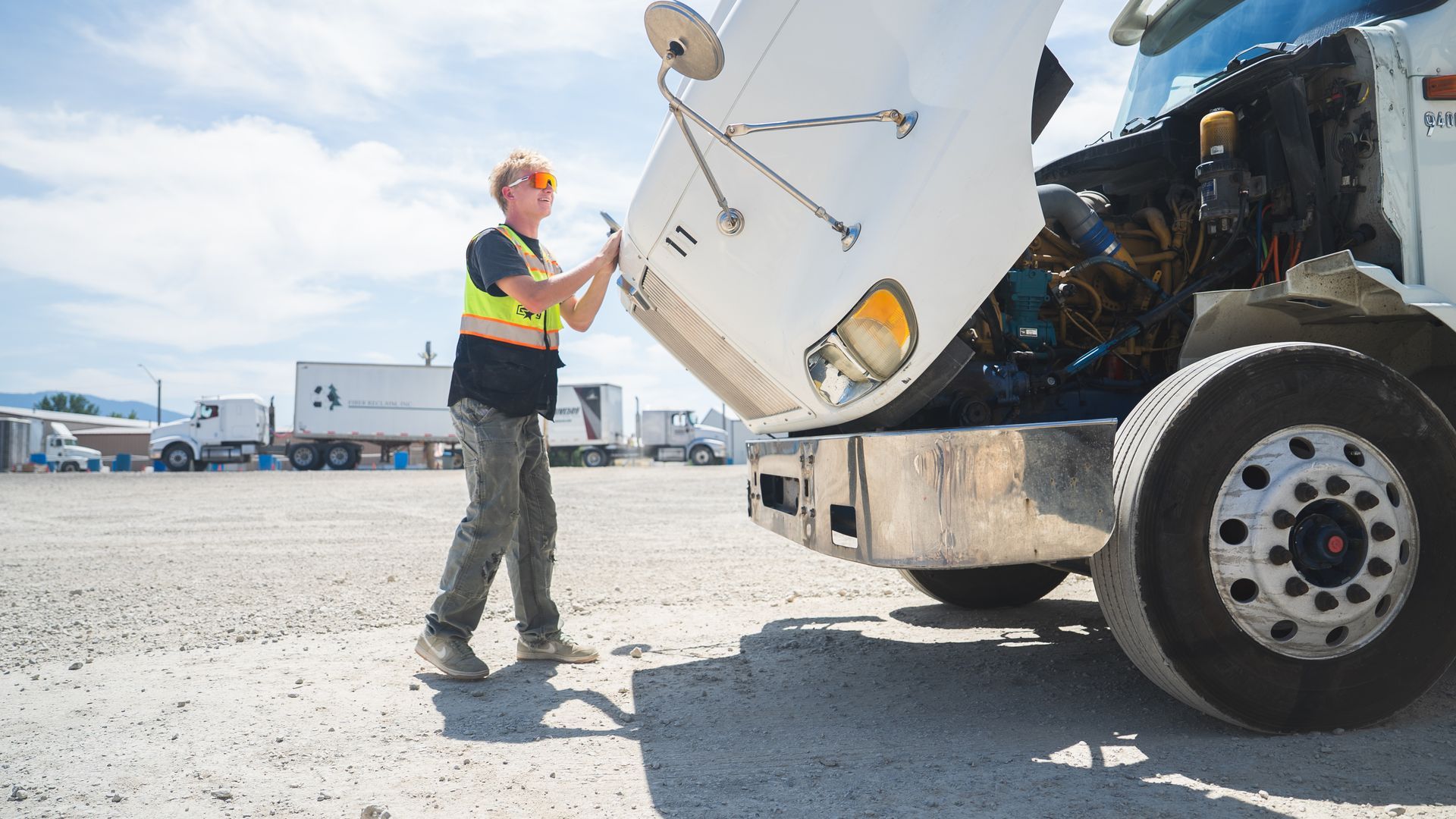 A cdl student is looking under the hood of a semi truck doing ELDT behind-the-wheel training