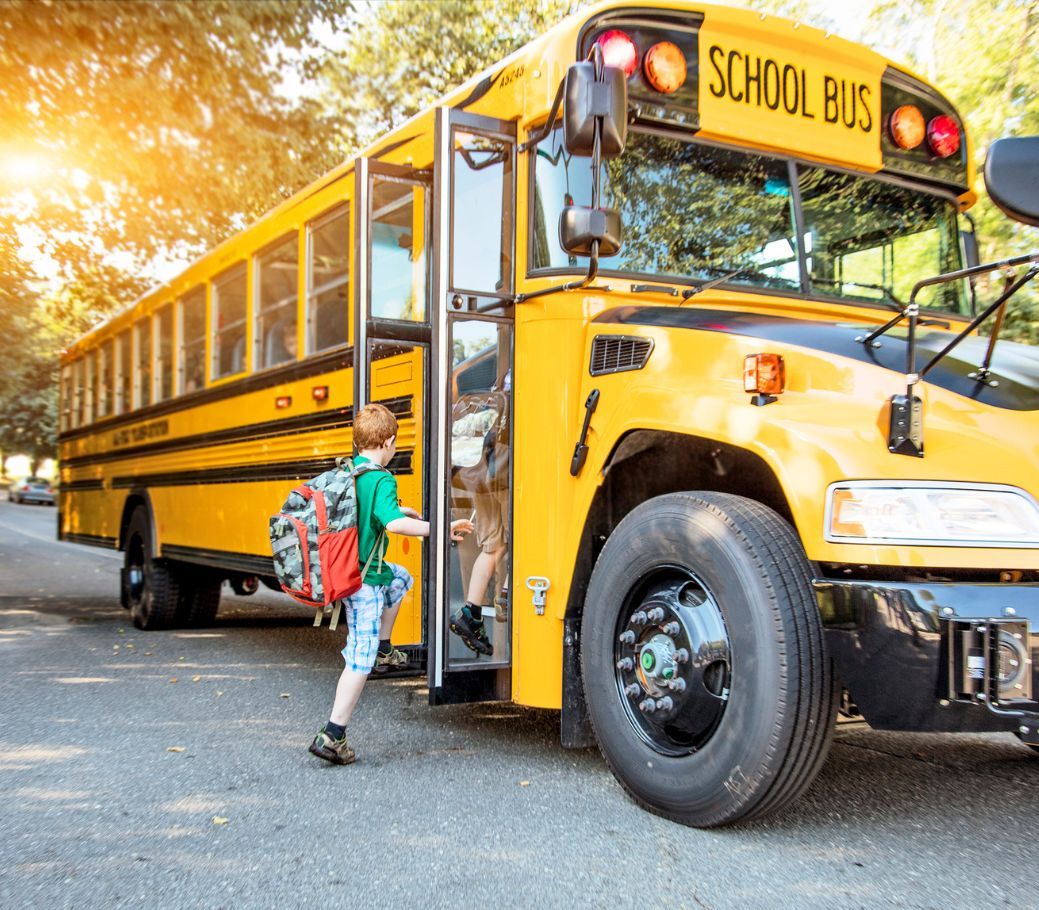 A boy is getting off a yellow school bus.
