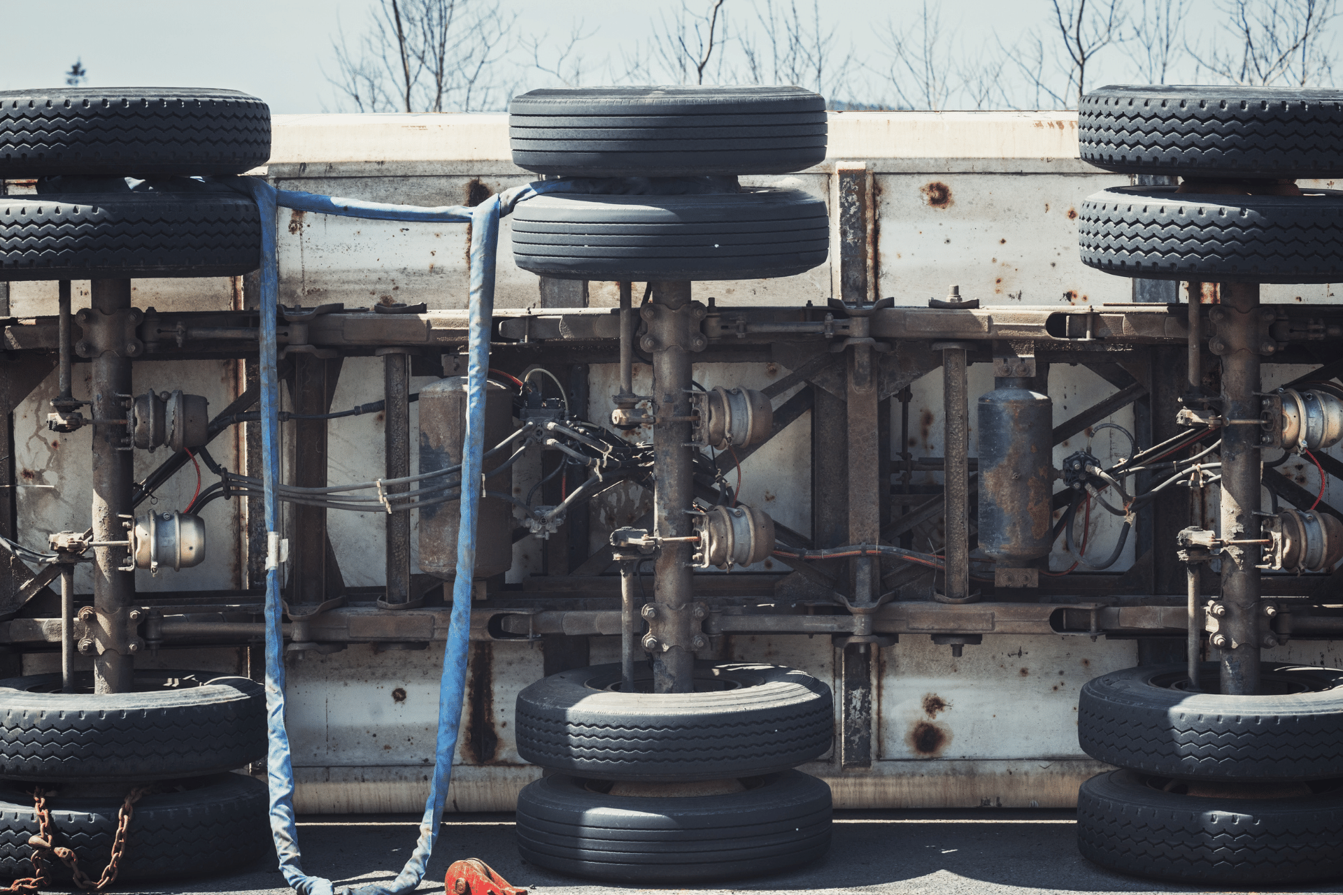 A truck is turned over on its side with tires stacked on top of it.