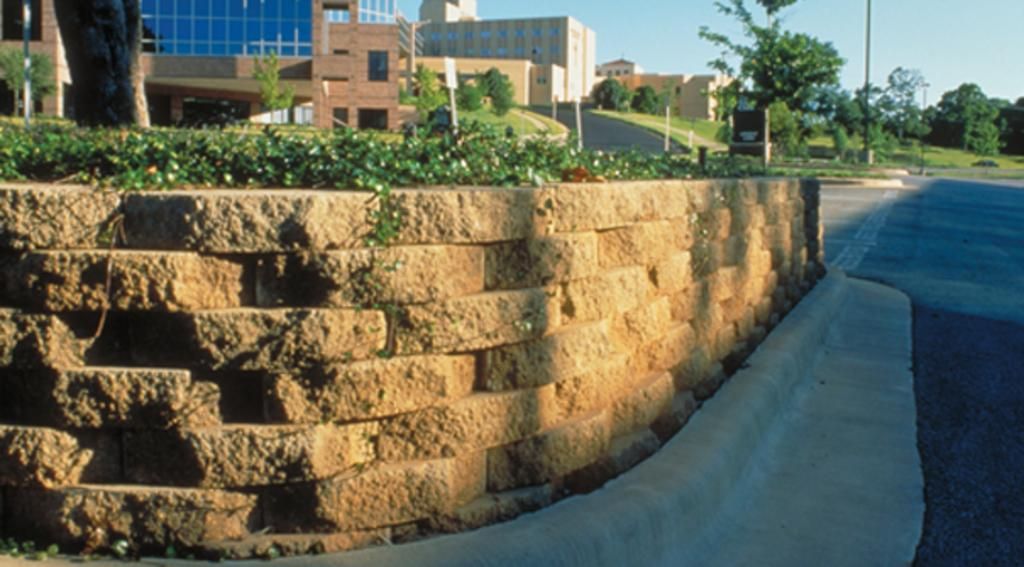 A stone wall along the side of a road with a building in the background