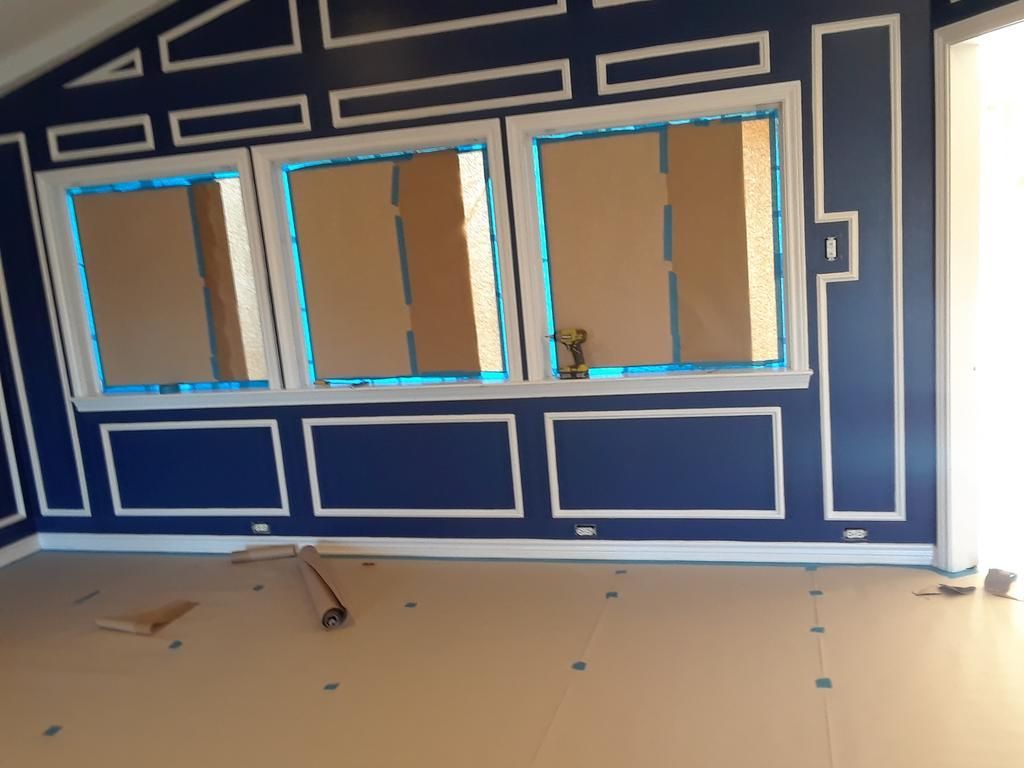 A room with blue walls and white trim is being painted