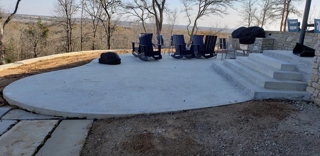 A large concrete patio with stairs and a fire pit in the middle of it.