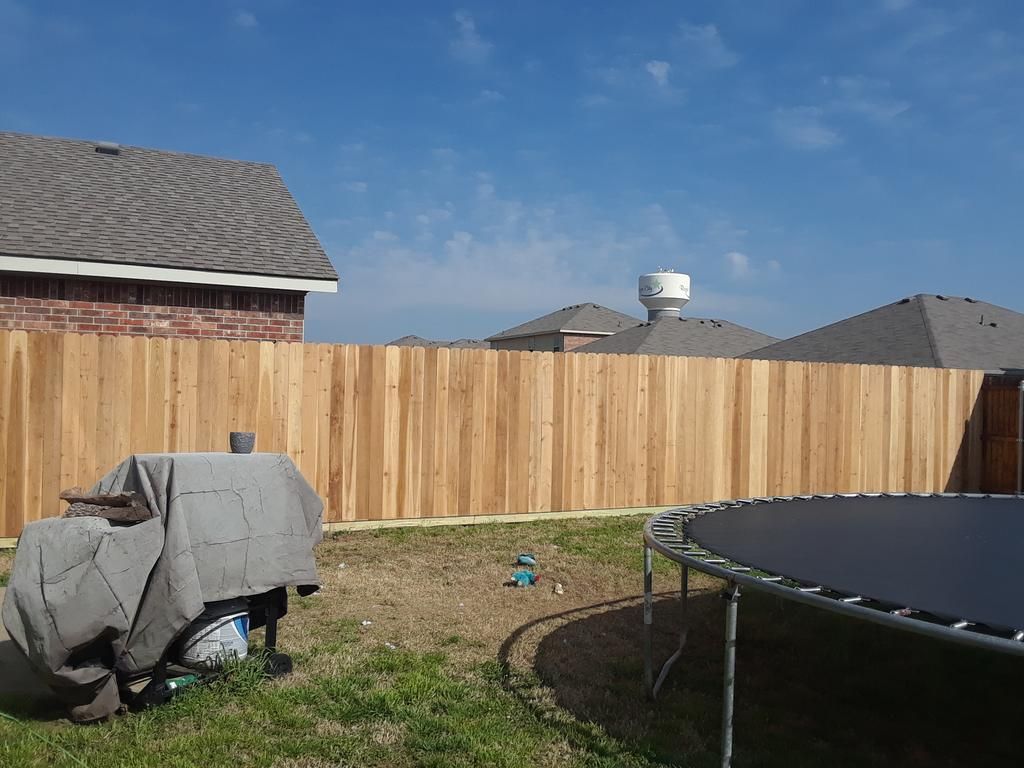 A wooden fence with a trampoline in front of it