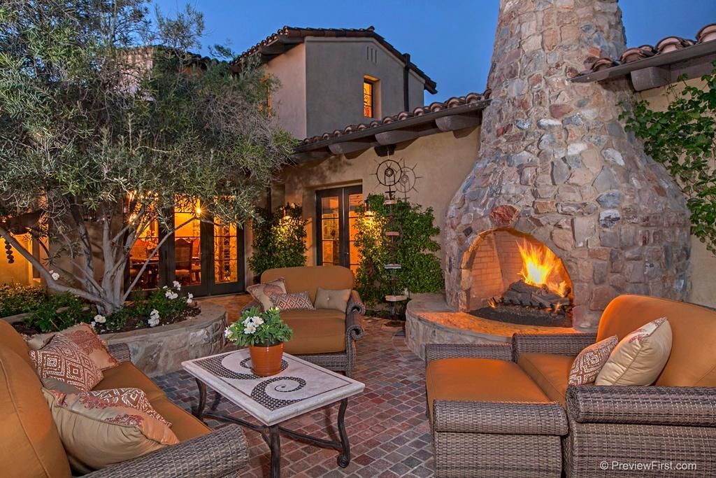 a patio with a fireplace and a couch and chairs