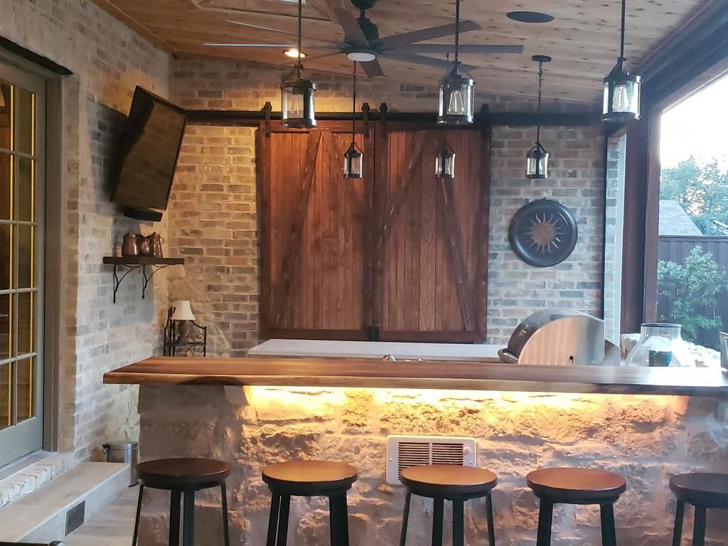 A kitchen with a bar and stools and a ceiling fan