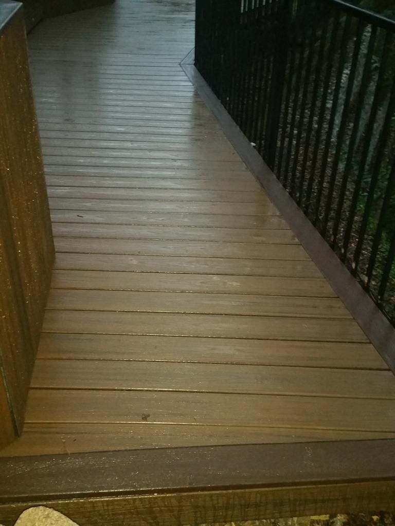 A wooden deck with a black railing and stairs