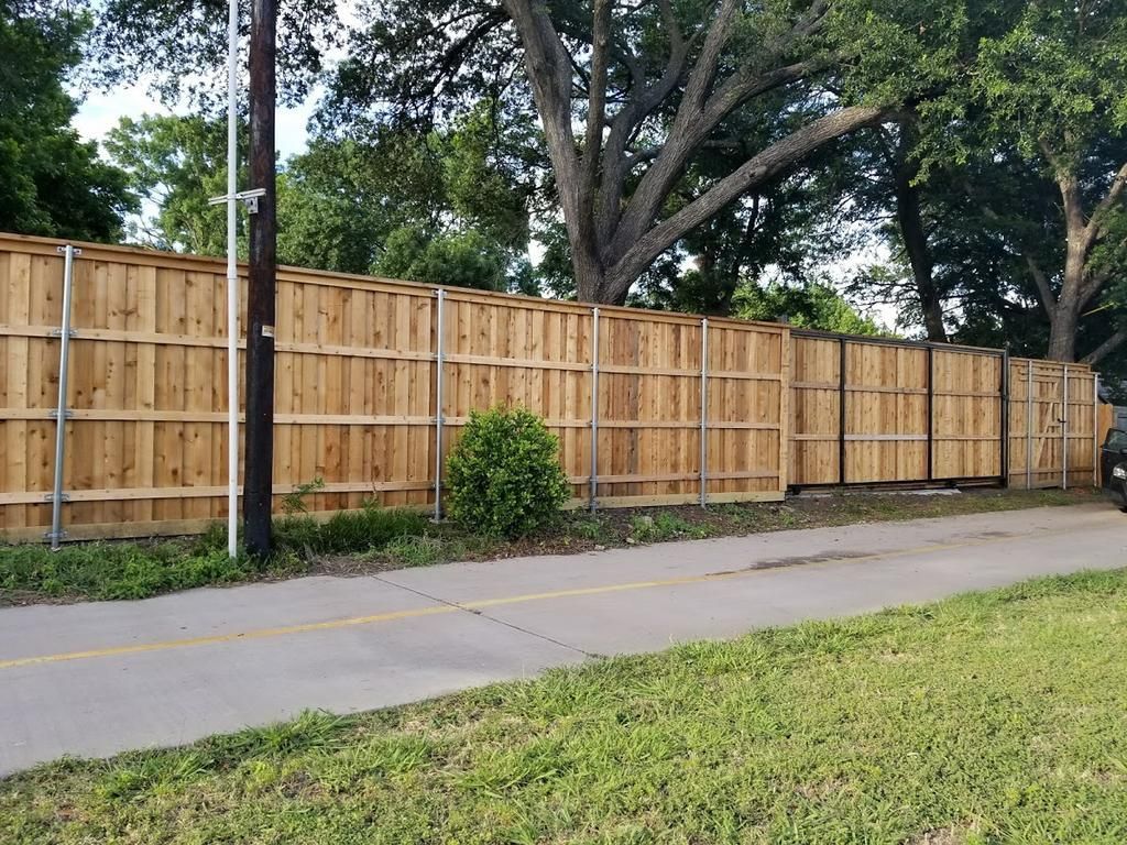 A wooden fence is along the side of a road.