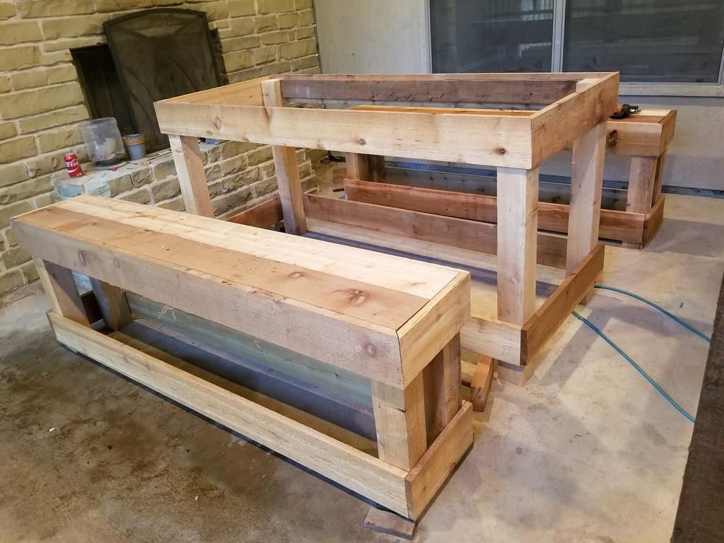 A wooden bench is sitting next to a wooden table in a room.