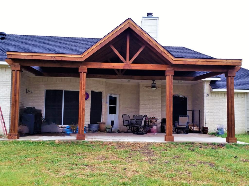 A white house with a large wooden porch in front of it.