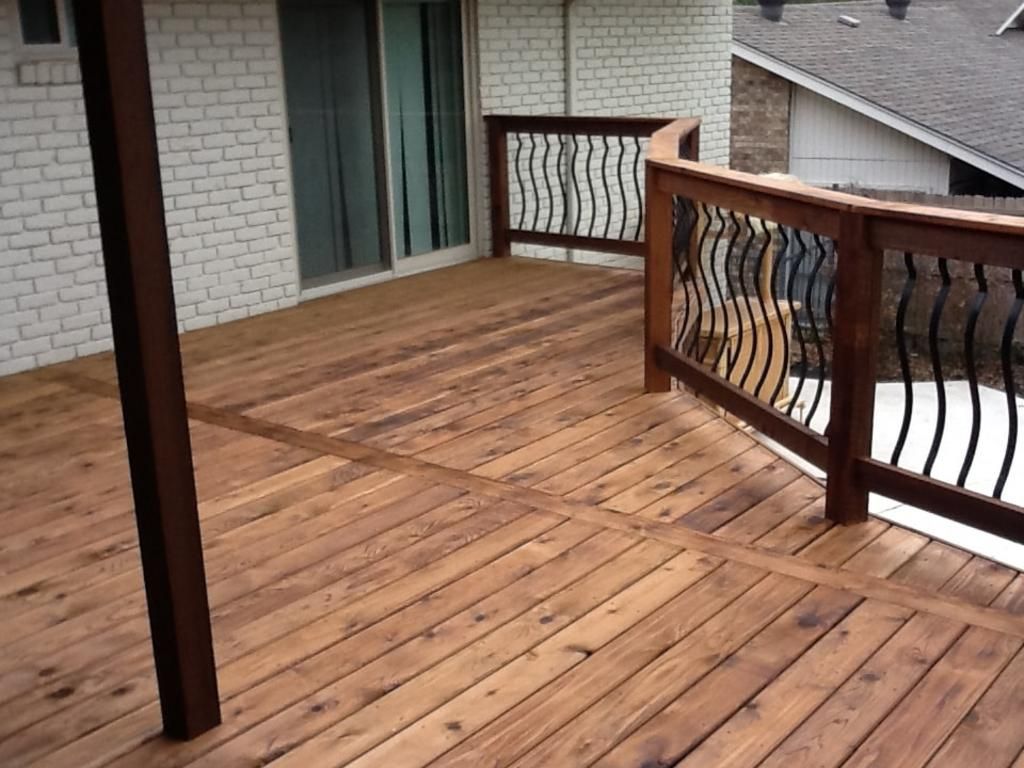 A wooden deck with a metal railing and a sliding glass door