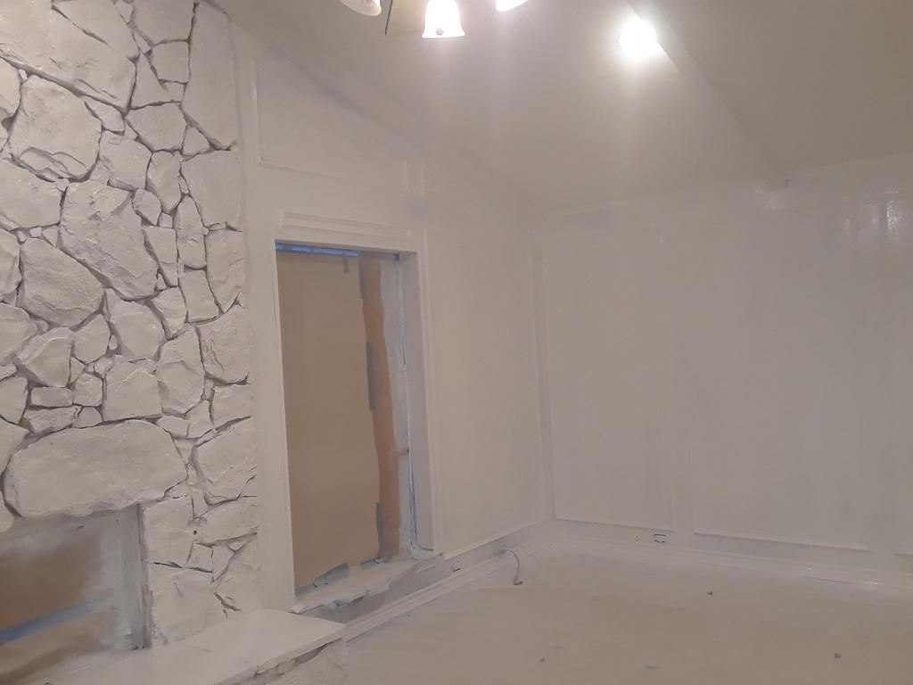 A room with white walls and a stone fireplace.