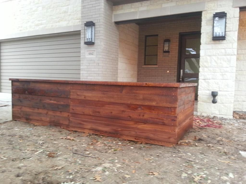 A wooden box is sitting in front of a brick building.