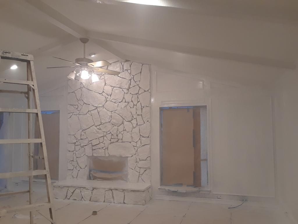 A living room with a fireplace and a ceiling fan.