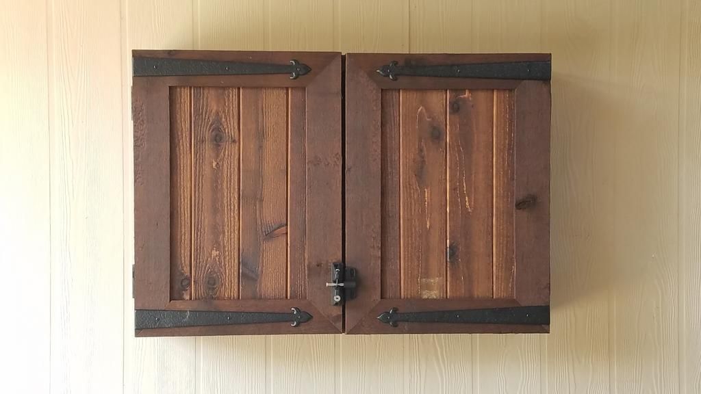 A wooden cabinet is hanging on a wooden wall.