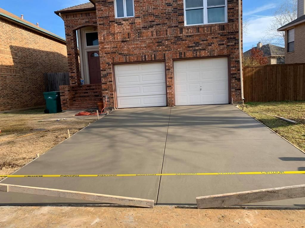 A brick house with a concrete driveway in front of it.